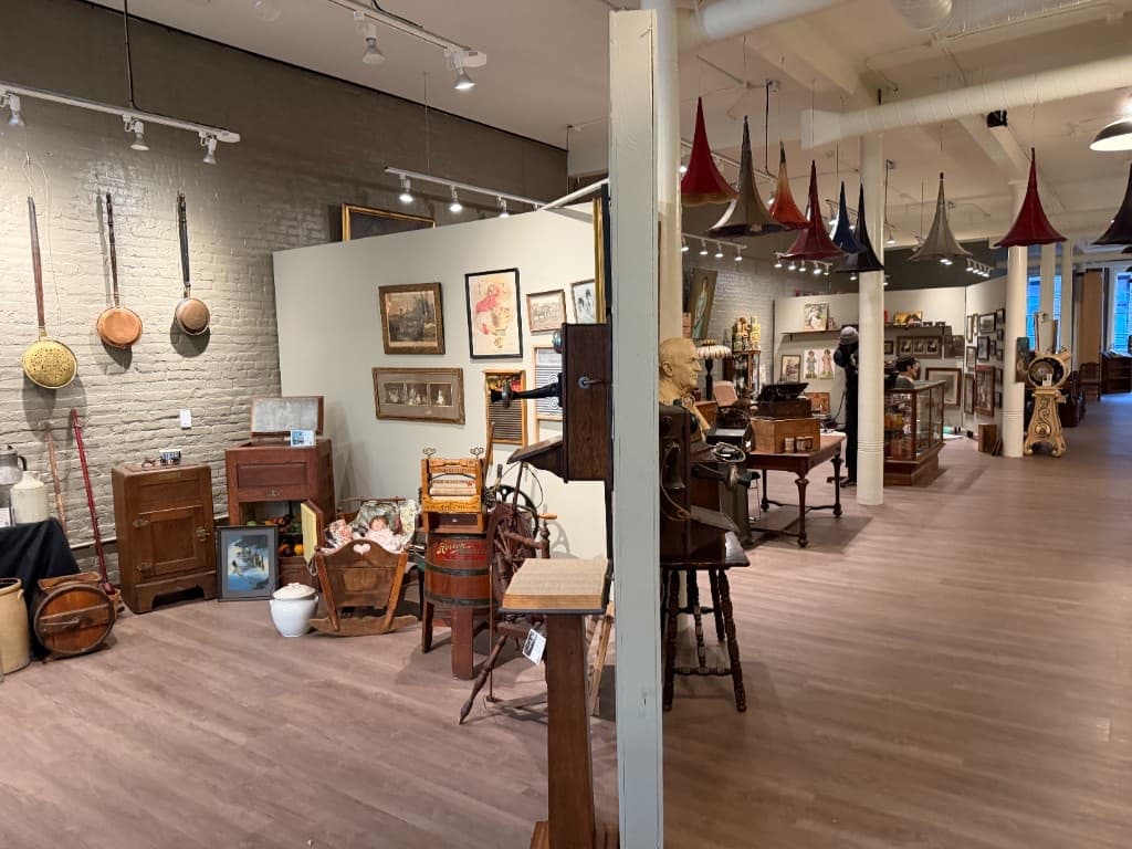 Open gallery view with suspended phonograph horns, domestic objects, portraits, and mechanical devices.