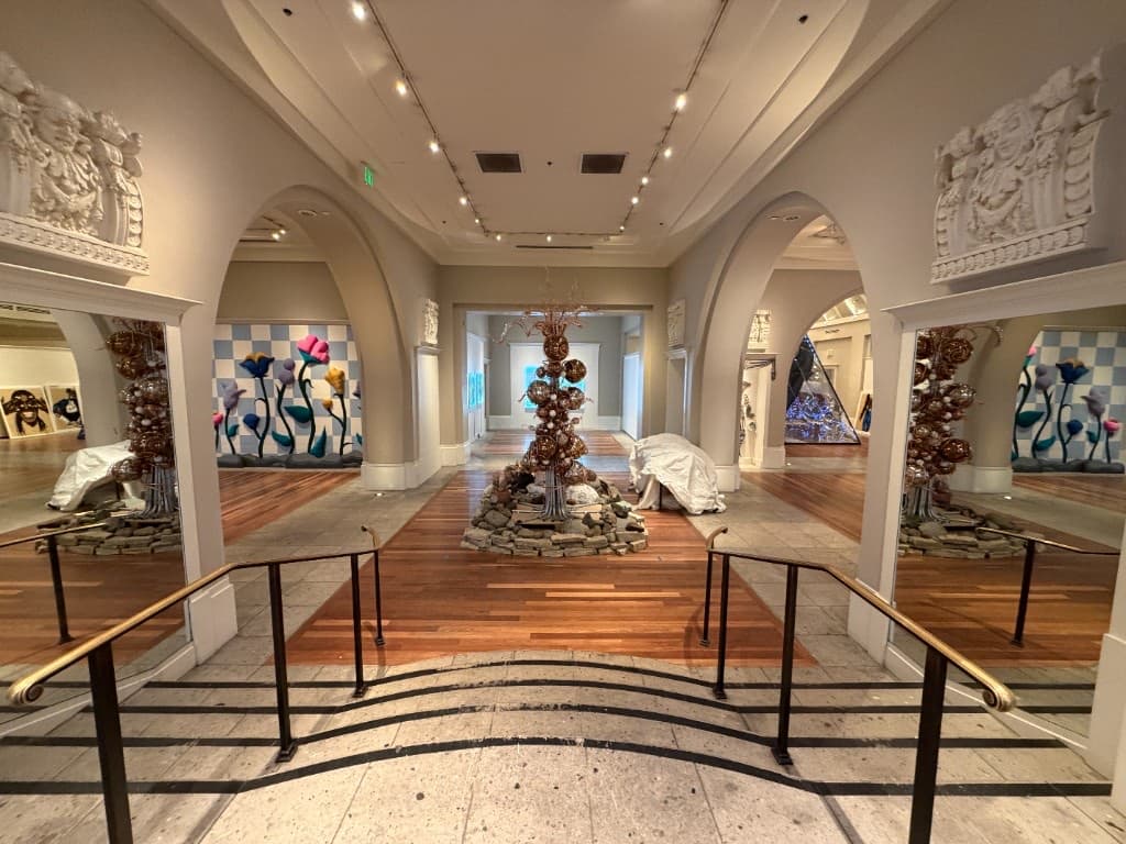 Inside the Coliseum: arched galleries of hand-blown glass, a copper-and-amber glass tree rising from a stone base, with blown-glass flower beds against blue-and-white tiled walls